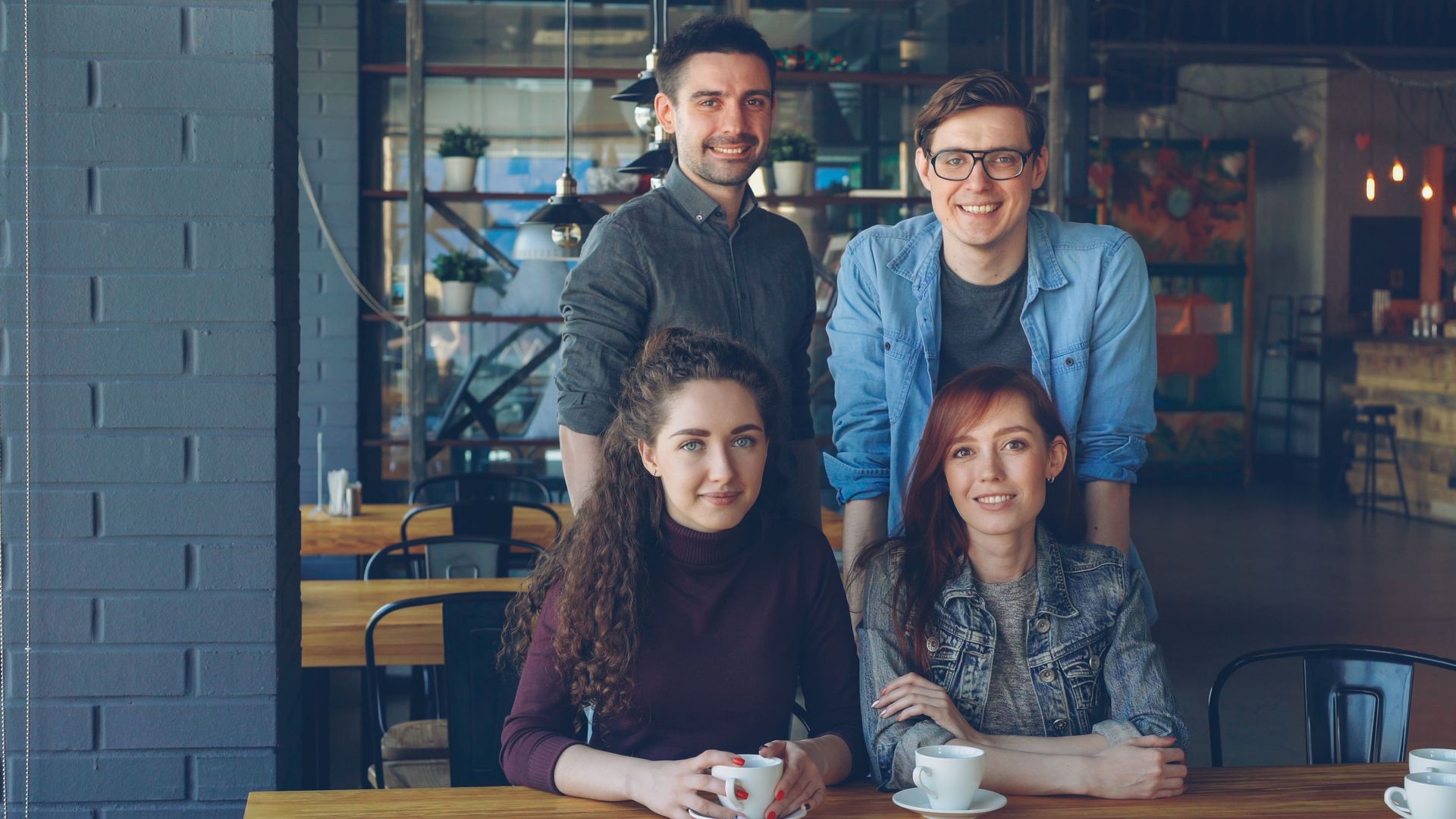 Four friends enjoying coffee at a modern cafe interior.